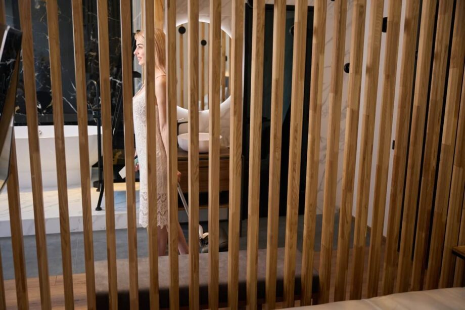 Eine Frau steht hinter beweglichen Holzlamellen für die Terrasse.