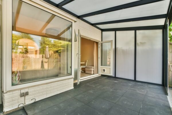 Ein moderner Innenhof mit großen Fenstern und sichtbaren Holzterrassenlamellen.