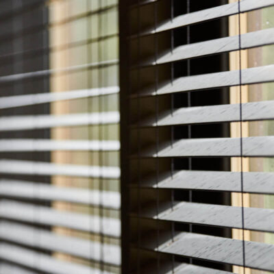 Ein Fenster zeigt ein System aus beweglichen Holzlamellen, die Licht regulieren.