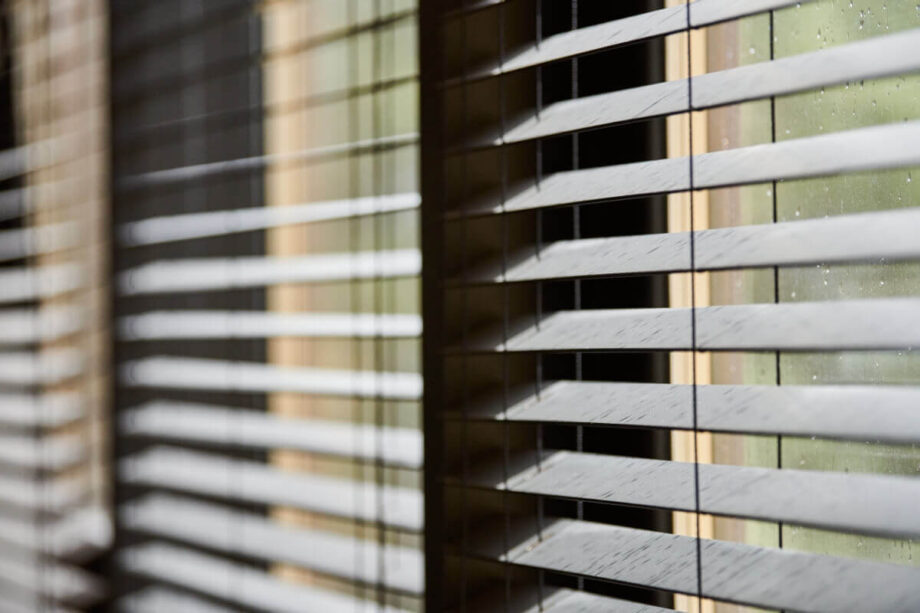 Ein Fenster zeigt ein System aus beweglichen Holzlamellen, die Licht regulieren.