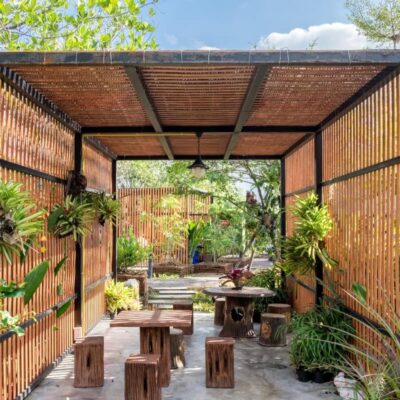 Ein moderner Holzgartenpavillon mit Pflanzen und Holzmöbeln.