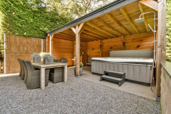 Eine gemütliche Terrasse mit Whirlpool, Essbereich und bewegliche Holzlamellen für Pergolen.