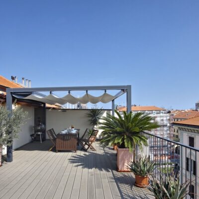 Eine Terrasse mit Holzterrassenlamellen, einigen Pflanzen und einem Esstisch.