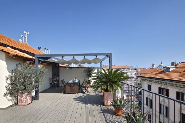 Eine Terrasse mit Holzterrassenlamellen, einigen Pflanzen und einem Esstisch.