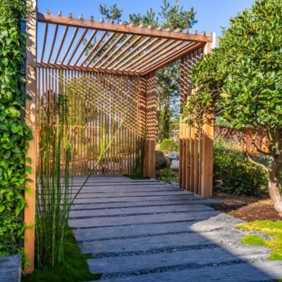 Ein moderner Gartenpavillon mit einem System aus beweglichen Holzlamellen bietet eine harmonische Verbindung zur Natur.